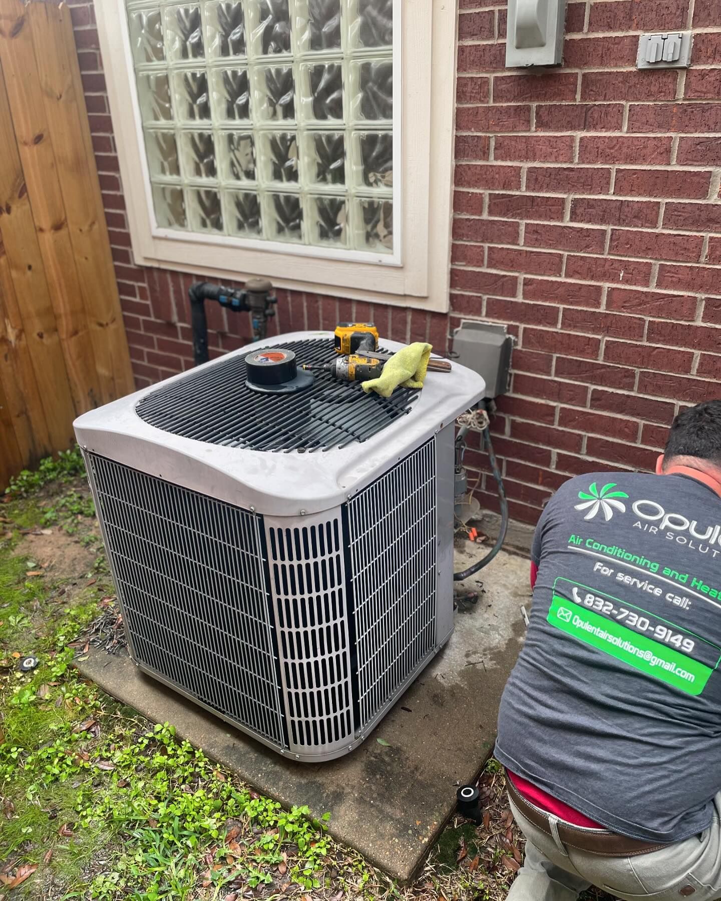 HVAC technician from Opulent Air Solutions working on outdoor HVAC condenser